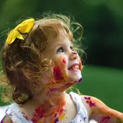 O fetita cu fata colorata de vopseluri rade