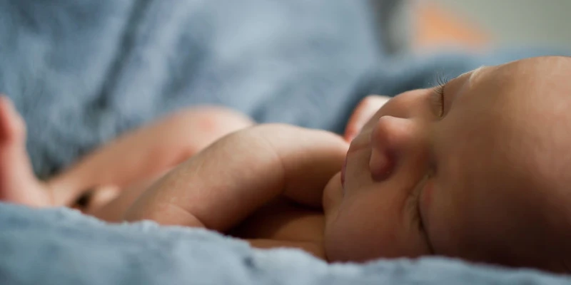 Un nou nascut vazut dinspre crestetul capului pe asternuturi albastre de spital